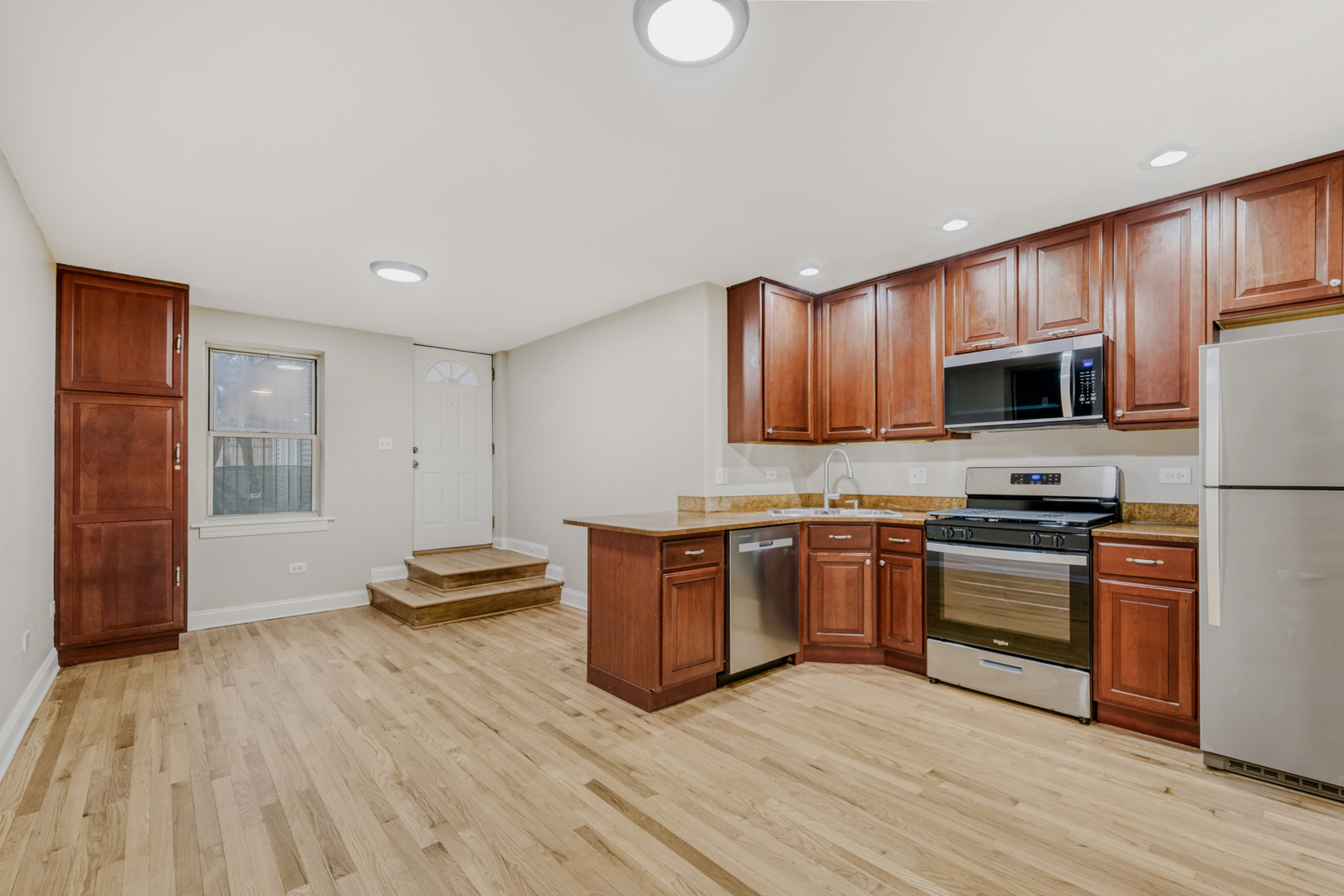 6450 North Bell Avenue, Unit G Chicago, IL 60645 - Photo 9 of 18 a kitchen with stainless steel appliances granite countertop a stove a sink dishwasher and a refrigerator with wooden floor