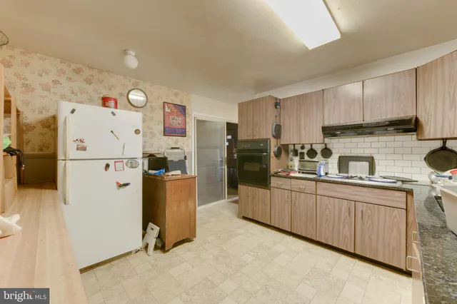 a kitchen with a refrigerator a stove top oven a sink and cabinets