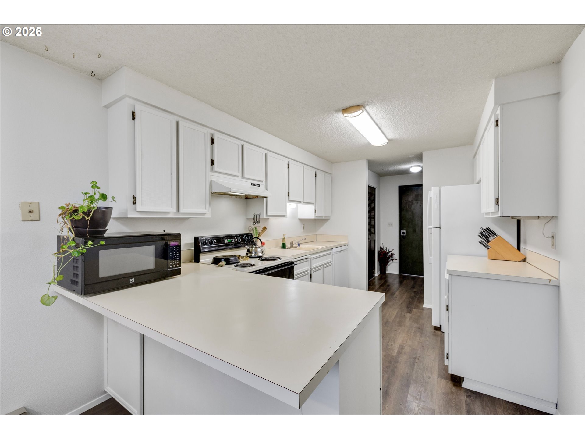 831 Northeast 90th Avenue Portland, OR 97220 - Photo 5 of 25 a kitchen with kitchen island a stove a sink a refrigerator white cabinets and wooden floor