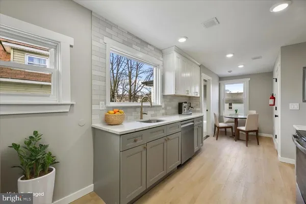 a large white kitchen with a sink and dishwasher a stove with wooden floor