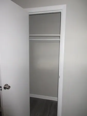 an empty room with wooden floor & closet area