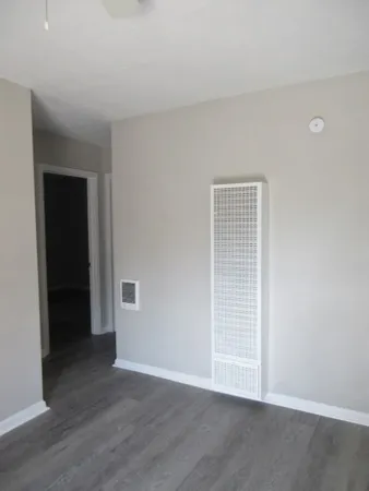 a view of an empty room with wooden floor and closet