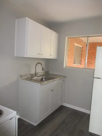 a view of a kitchen with sink and dishwasher with wooden floor