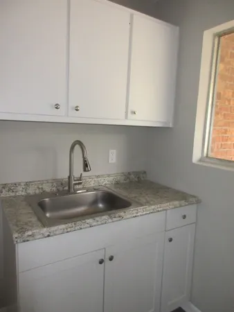 a kitchen with granite countertop white cabinets and a sink