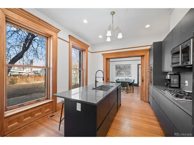 a living room with stainless steel appliances granite countertop furniture wooden floor and a kitchen view
