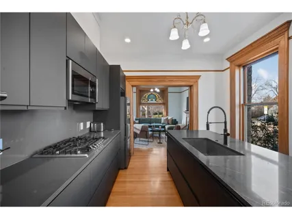 a view of a kitchen with kitchen island a sink wooden floor and stainless steel appliances