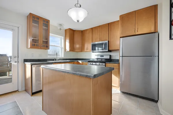 a kitchen with granite countertop stainless steel appliances a refrigerator a sink and cabinets