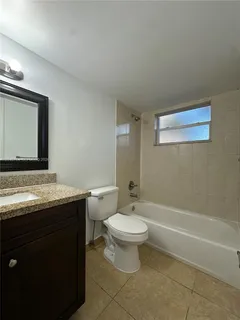 a bathroom with a granite countertop sink a toilet a mirror and bathtub