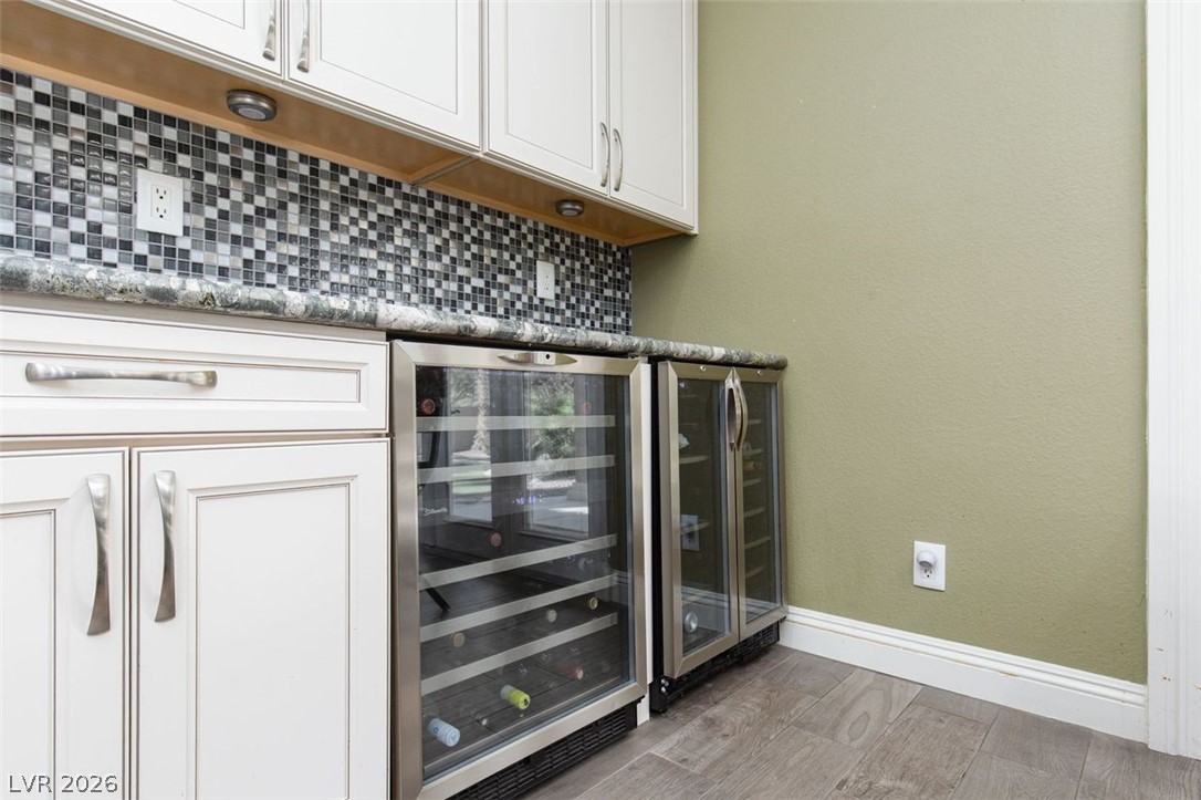 4670 Los Rancheros Avenue Las Vegas, NV 89129 - Photo 19 of 57 Custom cabinetry and built-in beverage coolers complement the stone countertops and mosaic tile backsplash.