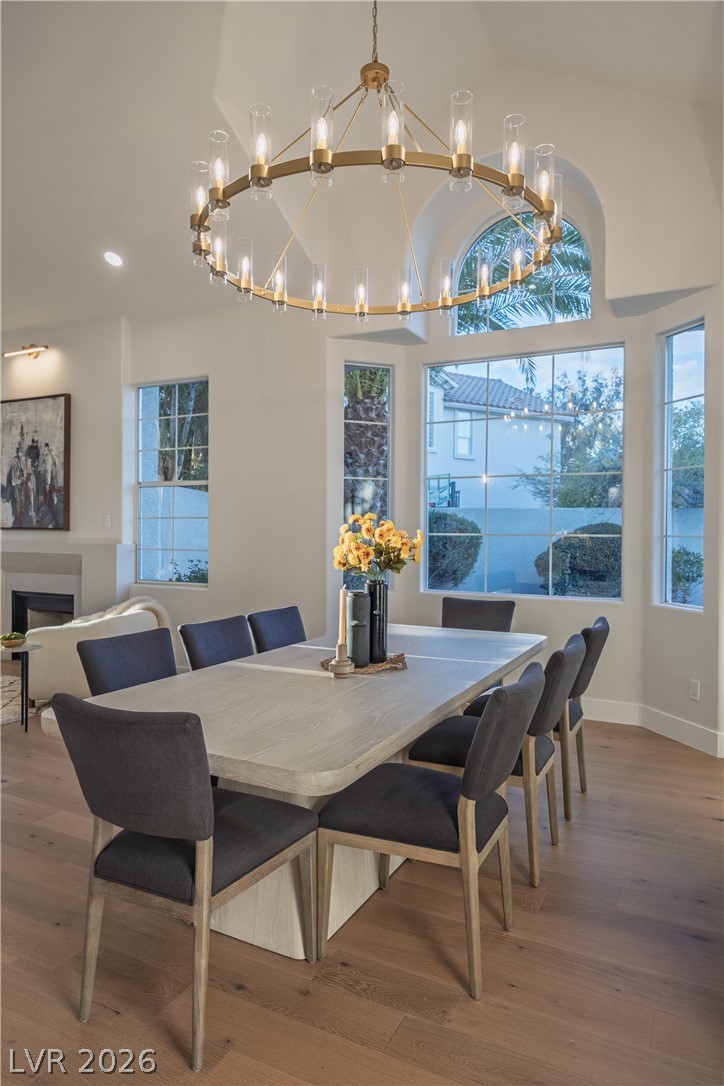 8800 Lusso Las Vegas, NV 89134 - Photo 24 of 85 Dining room with a chandelier, light wood-style floors, a fireplace, and vaulted ceiling