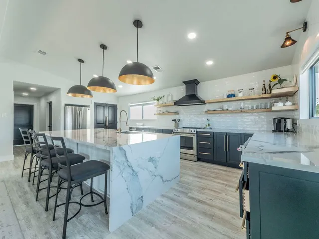 a kitchen with stainless steel appliances granite countertop a sink a stove and a wooden floors