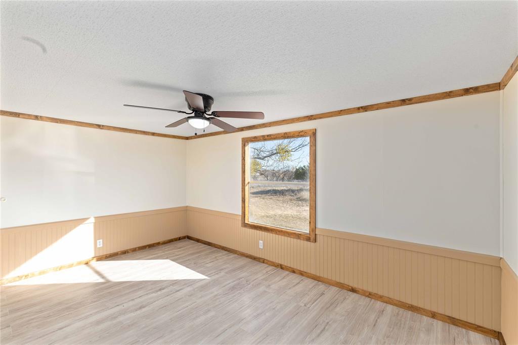 3393 Doe Trail Road Brownwood, TX 76801 - Photo 11 of 29 an empty room with wooden floor fan and windows
