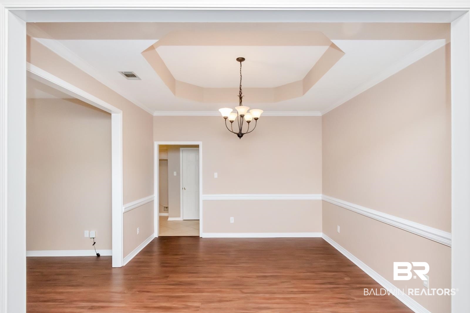 6117 Lennox Place Mobile, AL 36693 - Photo 3 of 39 Spare room featuring visible vents, baseboards, a tray ceiling, light wood finished floors, and a notable chandelier
