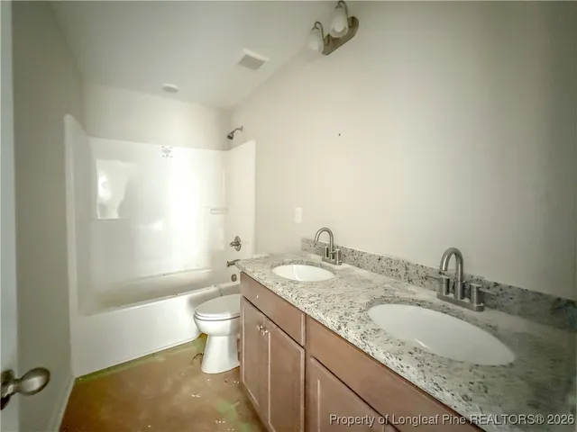 a bathroom with a granite countertop sink mirror vanity and toilet