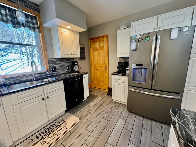 a kitchen with stainless steel appliances a refrigerator a sink and wooden floors