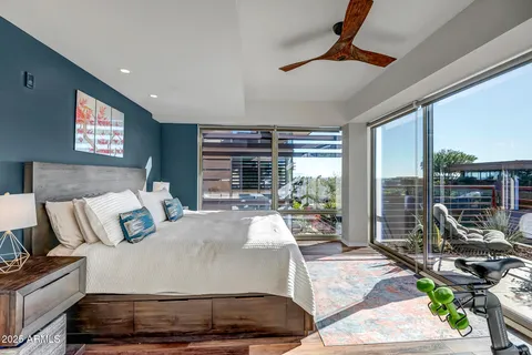 a bedroom with a bed a flat screen tv and a large window