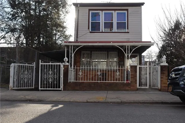 a view of a house with a small yard and large trees
