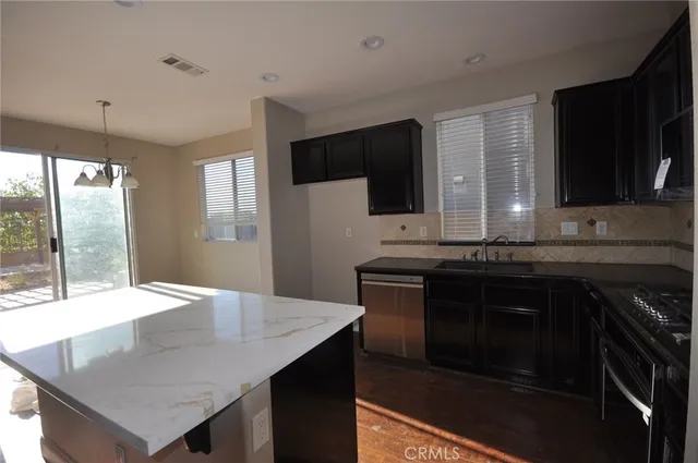 a kitchen with granite countertop a stove a sink and a microwave