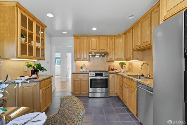 a kitchen with stainless steel appliances granite countertop a stove a sink dishwasher and a refrigerator