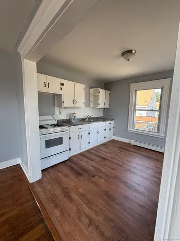 a kitchen with granite countertop a stove a sink and a refrigerator