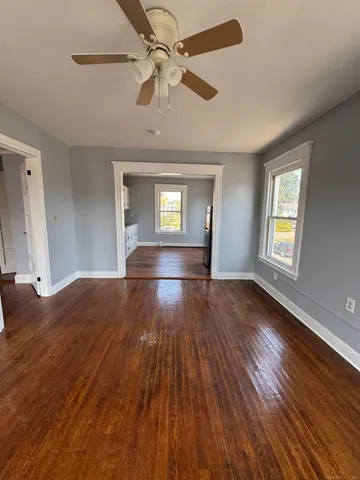 a view of empty room with wooden floor and fan