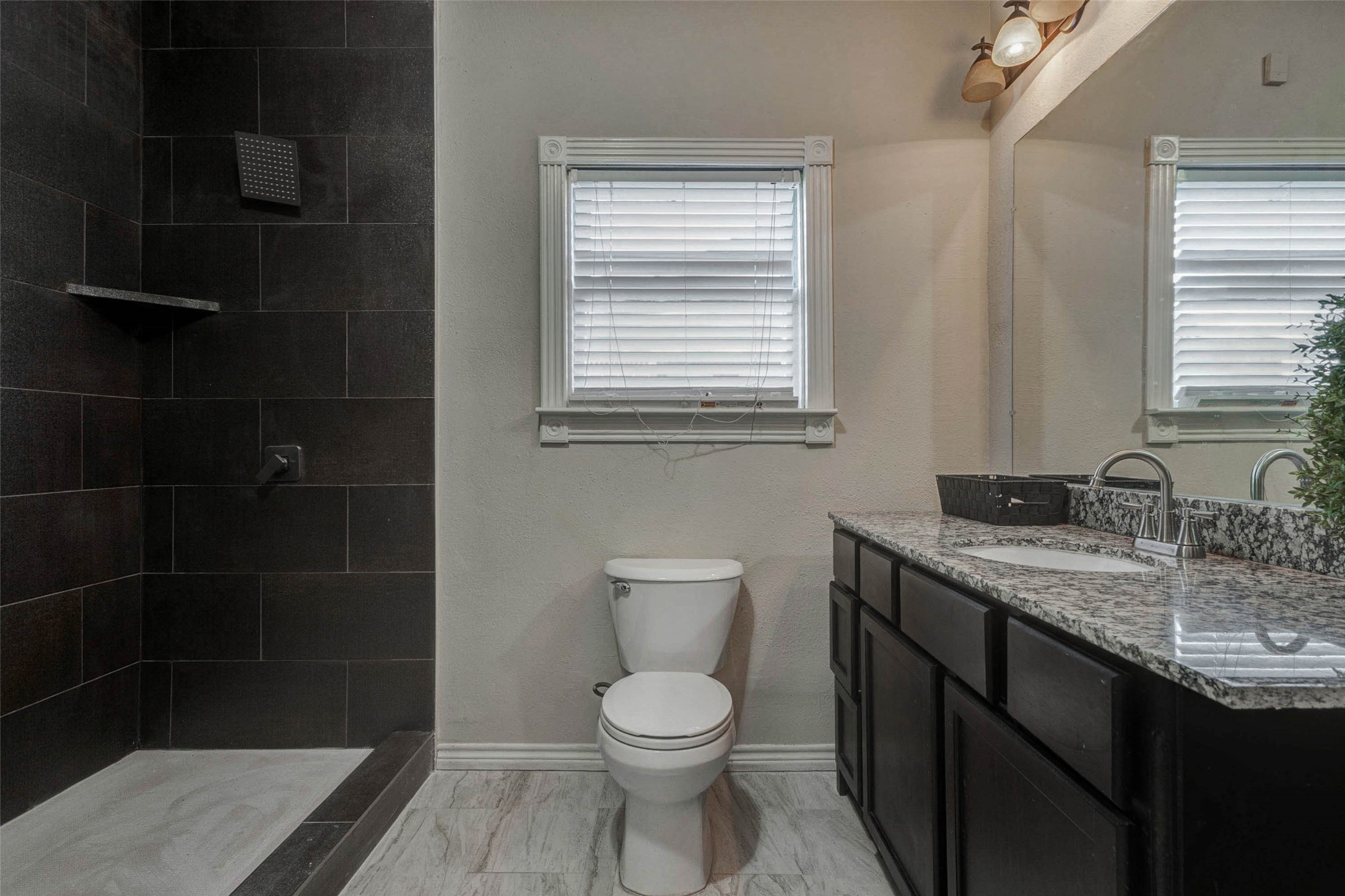 2410 Cleburne Street Houston, TX 77004 - Photo 11 of 27 a bathroom with a granite countertop toilet a sink a mirror and a shower