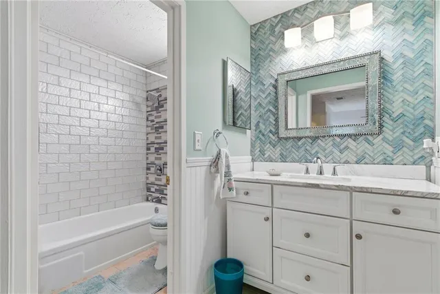a bathroom with a granite countertop sink a mirror and a bathtub