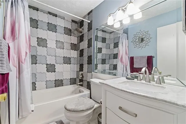 a bathroom with a sink a toilet a mirror a bathtub and shower