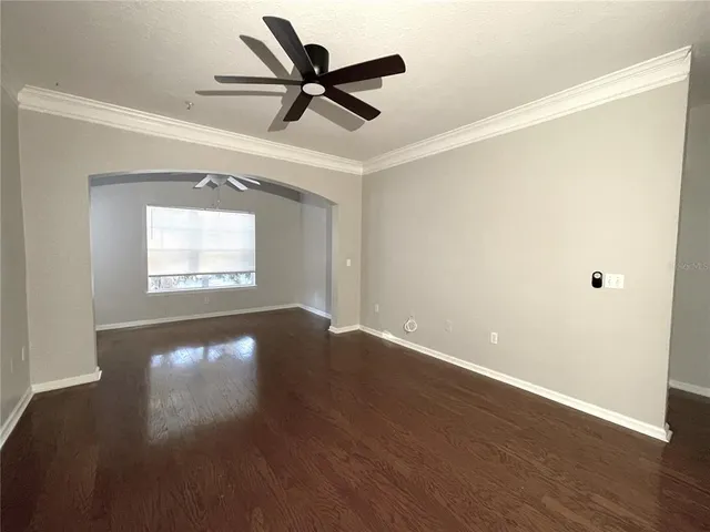 an empty room with wooden floor fan and windows