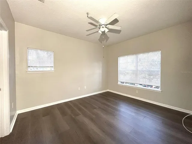 a view of an empty room with a window and wooden floor