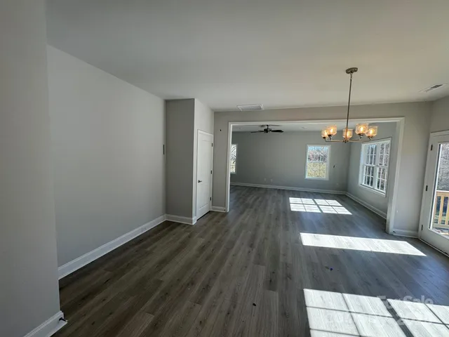 a view of a room with wooden floor a ceiling fan and window