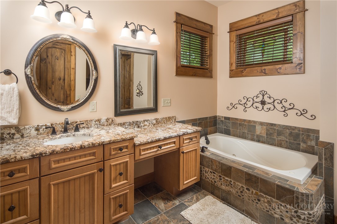 115 Passionflower Trail Boone, NC 28607 - Photo 23 of 50 a bathroom with a granite countertop sink a mirror a vanity and bathtub