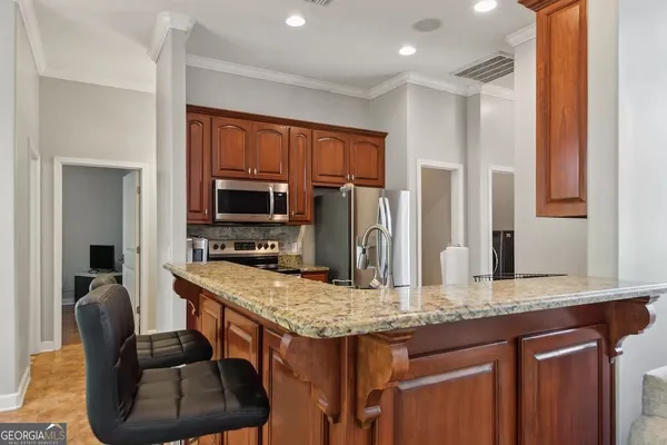 a kitchen with kitchen island granite countertop wooden cabinets and a refrigerator