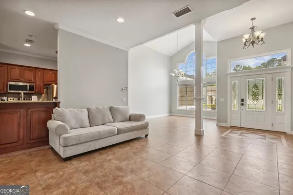 a living room with furniture a chandelier and kitchen view