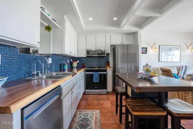 a kitchen with stainless steel appliances granite countertop a refrigerator a sink a stove a dining table and chairs