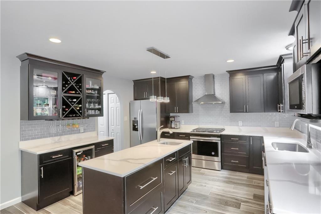 1075 Rural Ridge Drive Cheswick, PA 15024 - Photo 4 of 25 Highlights of this updated kitchen include showcase cabinetry, built in wine rack, modern pendent lighting above the endless Quartz island, stainless steel appliances, modern tile flooring and a striking complimenting backsplash,.