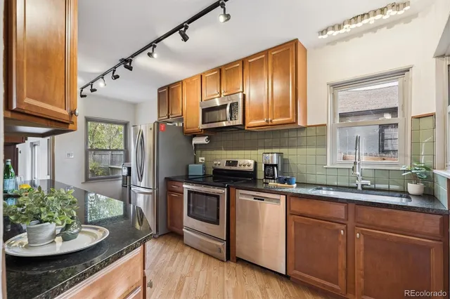 a kitchen with stainless steel appliances granite countertop a sink a stove and cabinets