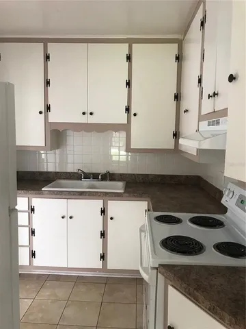 a kitchen with granite countertop white cabinets and a stove