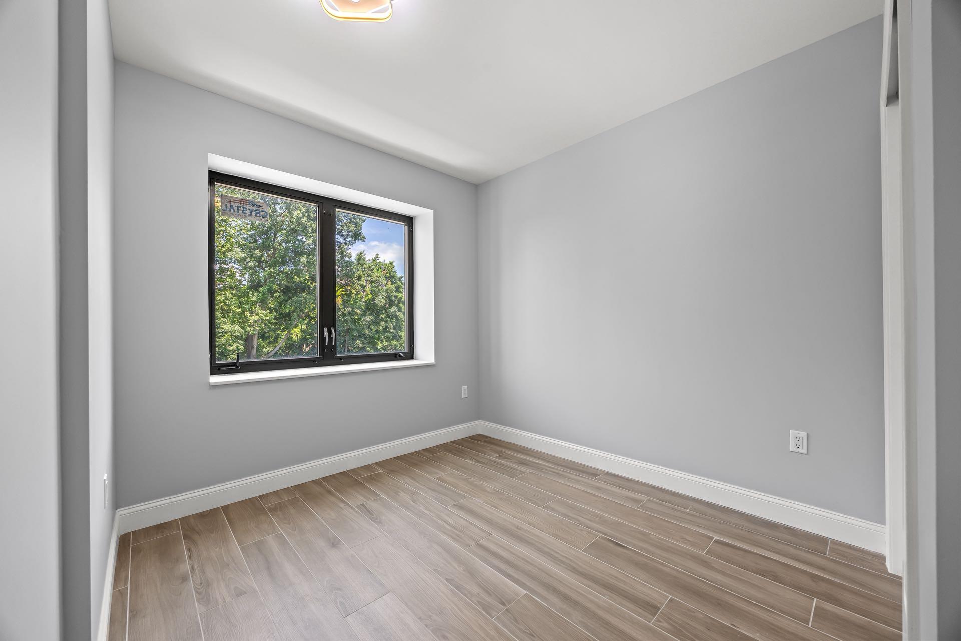 132-25 41st Avenue, Unit 5B Queens, NY 11355 - Photo 8 of 11 an empty room with wooden floor and windows