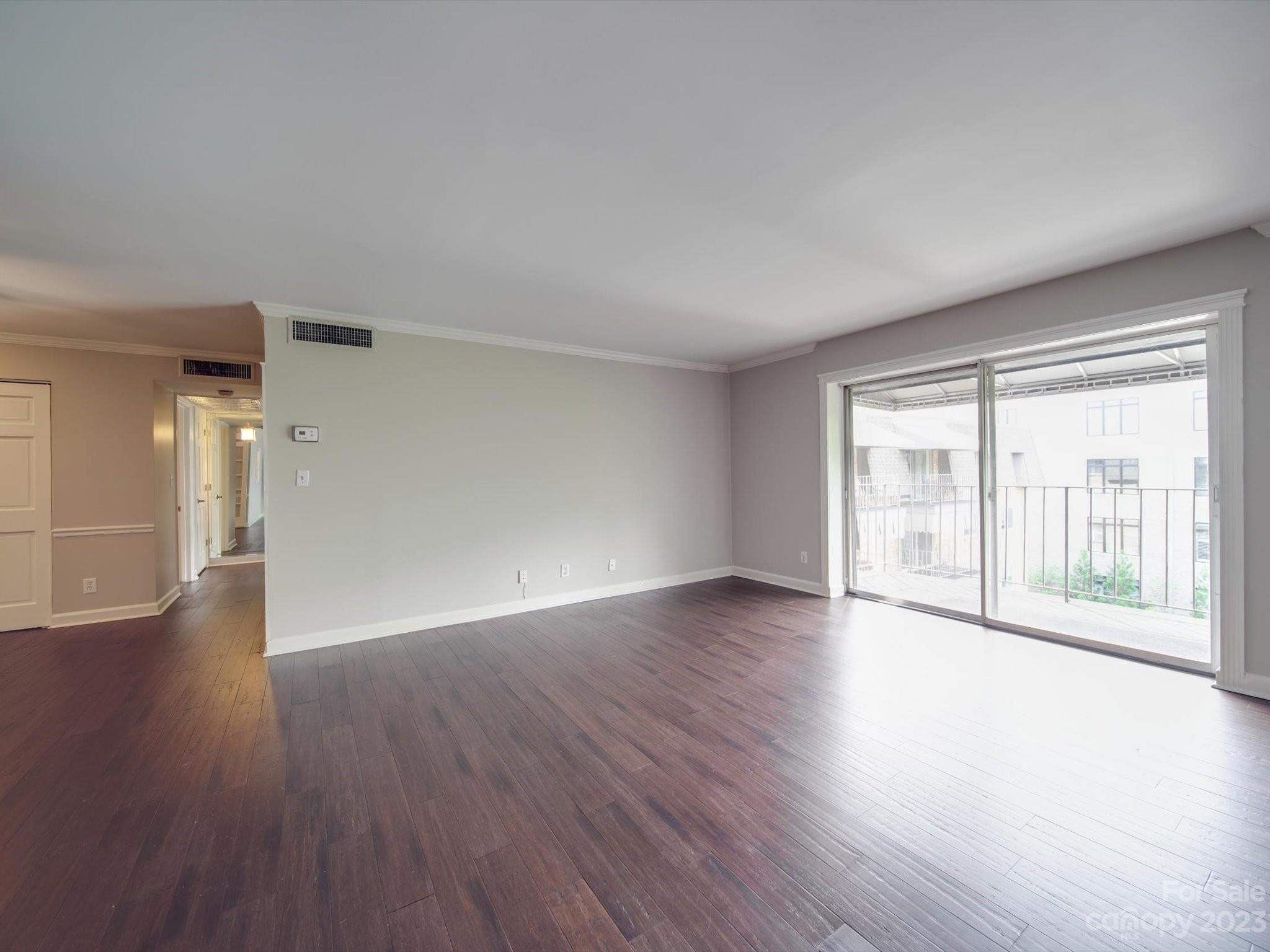 1323 Queens Road, Unit 402 Charlotte, NC 28207 - Photo 5 of 26 a view of an empty room with wooden floor and a window
