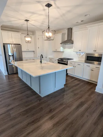 a large kitchen with stainless steel appliances granite countertop wooden floors wooden cabinets a stove and a sink