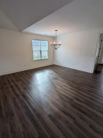 an empty room with wooden floor cabinet and windows