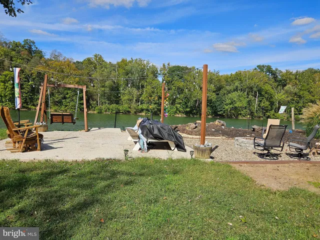 a view of a swimming pool with a bench and trees in the background
