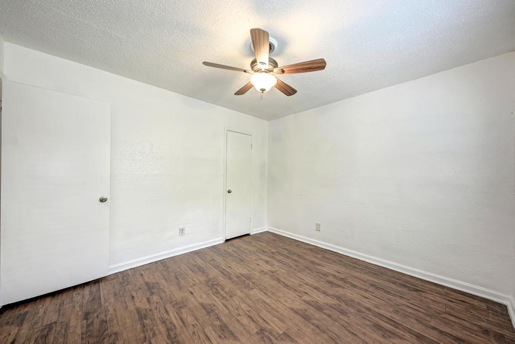2401 Manor Road, Unit 133 Austin, TX 78722 - Photo 20 of 20 Rich hardwood floors complement the neutral palette, creating a versatile bedroom retreat.