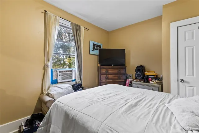 a bedroom with a bed and a flat tv screen on a dresser