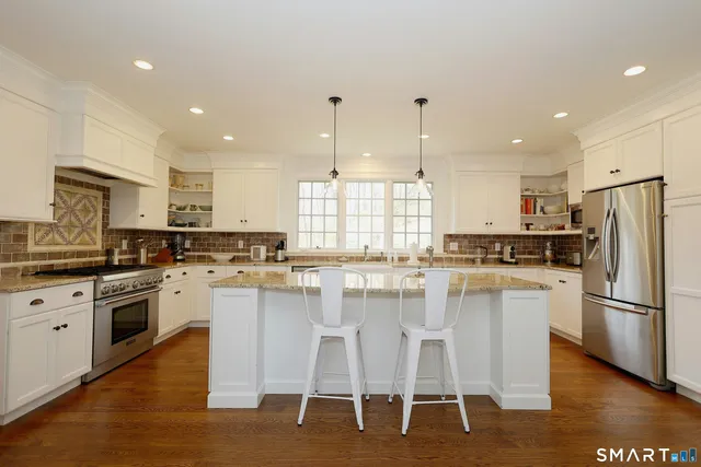a kitchen with a chandelier stainless steel appliances and white cabinets