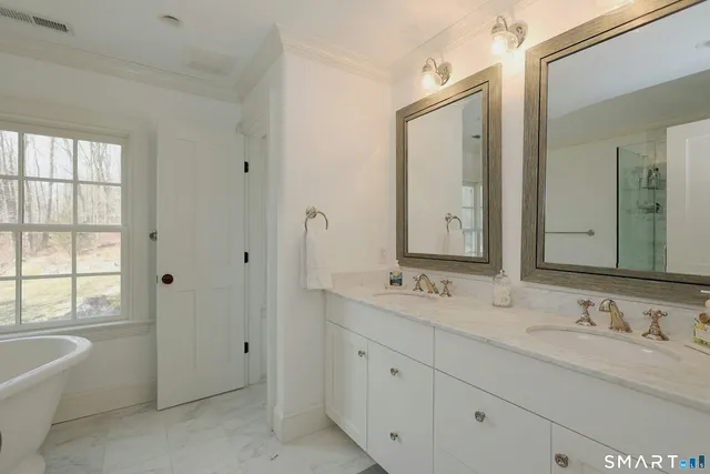 a bathroom with double vanity sinks a mirror and a bathtub