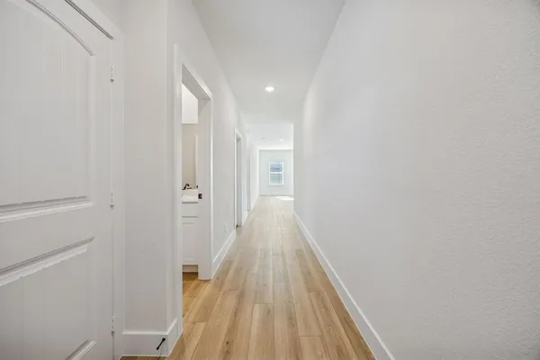 a view of a hallway with wooden floor and a bathroom
