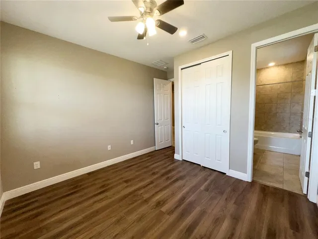 an empty room with wooden floor and closet area