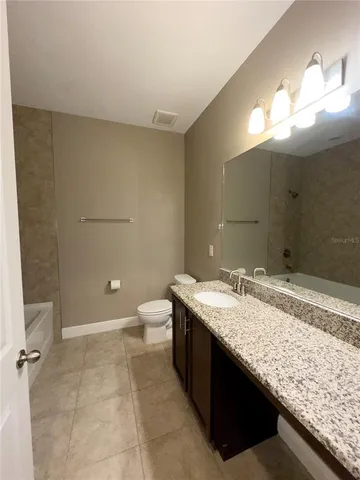a bathroom with a granite countertop sink a toilet and a mirror